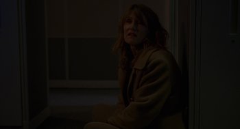 Movie still from “Certain Women” (2016), directed by Kelly Reichardt – A woman sitting on a chair in a dark room; Medium shot, Low angle
