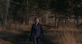Movie still from “Certain Women” (2016), directed by Kelly Reichardt – A woman walking through the woods wearing gloves and a hat; Medium shot, Low angle