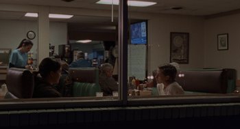 Movie still from “Certain Women” (2016), directed by Kelly Reichardt – A group of people sitting at a table in front of a window; Wide shot, Over the shoulder angle