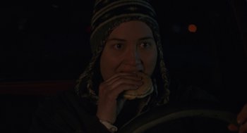 Movie still from “Certain Women” (2016), directed by Kelly Reichardt – A person sitting in a car eating a hot dog; Close Up shot, High angle