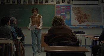 Movie still from “Certain Women” (2016), directed by Kelly Reichardt – A woman standing in front of a chalkboard holding papers; Wide shot, Over the shoulder angle