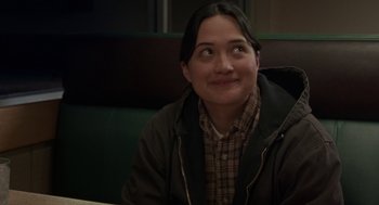 Movie still from “Certain Women” (2016), directed by Kelly Reichardt – A woman sitting at a table in front of a window; Close Up shot, Over the shoulder angle