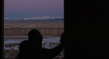 Movie still from “Certain Women” (2016), directed by Kelly Reichardt – A man standing in front of a fence looking out a window at the mountains; Extreme Wide shot, Over the shoulder angle