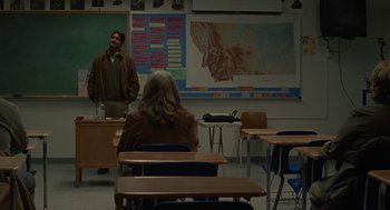 Movie still from “Certain Women” (2016), directed by Kelly Reichardt – A man standing in front of a woman in a classroom; Wide shot, Over the shoulder angle