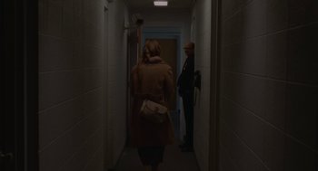 Movie still from “Certain Women” (2016), directed by Kelly Reichardt – Two people are walking down a hallway in a building; Wide shot, Over the shoulder angle