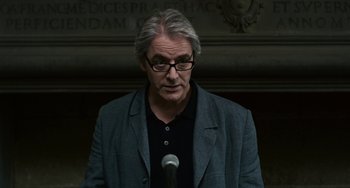 Movie still from “Certified Copy” (2010), directed by Abbas Kiarostami – An older man with glasses is speaking into a microphone; Close Up shot, Low angle