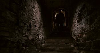 Movie still from “Certified Copy” (2010), directed by Abbas Kiarostami – A person walking down a set of stairs; Wide shot, Low angle