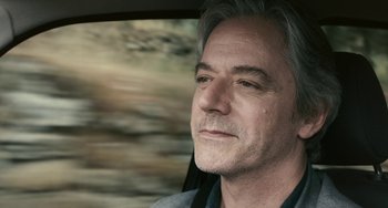 Movie still from “Certified Copy” (2010), directed by Abbas Kiarostami – A person sitting in a car; Close Up shot, Over the shoulder angle