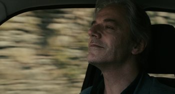 Movie still from “Certified Copy” (2010), directed by Abbas Kiarostami – A person in a car looking out the window; Close Up shot, Low angle