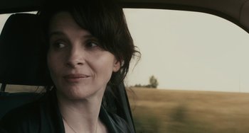 Movie still from “Certified Copy” (2010), directed by Abbas Kiarostami – A person in a car looking out the window; Close Up shot, Over the shoulder angle