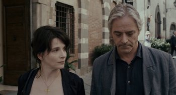Movie still from “Certified Copy” (2010), directed by Abbas Kiarostami – A man and a woman standing next to each other on the sidewalk; Close Up shot, Over the shoulder angle