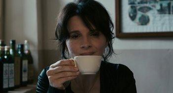 Movie still from “Certified Copy” (2010), directed by Abbas Kiarostami – A woman holding a cup of coffee in her hands; Close Up shot, High angle