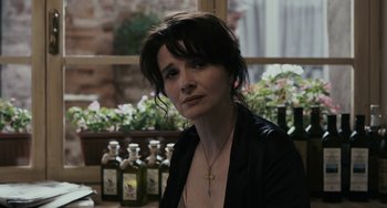 Movie still from “Certified Copy” (2010), directed by Abbas Kiarostami – A woman sitting in front of some bottles; Close Up shot, Over the shoulder angle