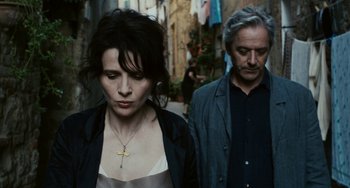Movie still from “Certified Copy” (2010), directed by Abbas Kiarostami – A man and a woman walking down a street; Medium shot, High angle