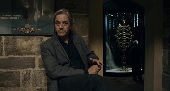 Movie still from “Certified Copy” (2010), directed by Abbas Kiarostami – A man sitting in front of a christmas tree in a room; Medium shot, Over the shoulder angle