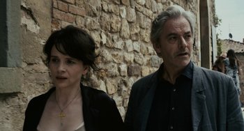 Movie still from “Certified Copy” (2010), directed by Abbas Kiarostami – A man and a woman standing in front of a brick wall; Close Up shot, High angle