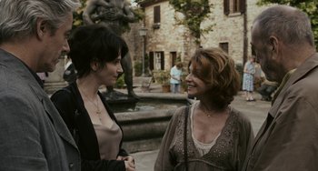 Movie still from “Certified Copy” (2010), directed by Abbas Kiarostami – Two women standing next to each other in front of a fountain; Medium shot, Over the shoulder angle