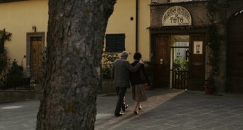 Movie still from “Certified Copy” (2010), directed by Abbas Kiarostami – A man and a woman walking down the sidewalk; Wide shot, Over the shoulder angle