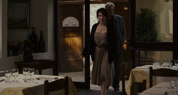 Movie still from “Certified Copy” (2010), directed by Abbas Kiarostami – A man and a woman are walking through a doorway; Medium shot, Over the shoulder angle