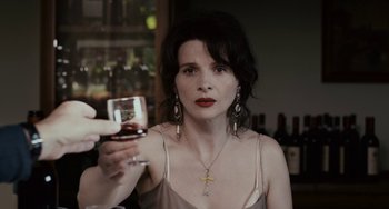 Movie still from “Certified Copy” (2010), directed by Abbas Kiarostami – A woman holding a glass of wine in her hand; Close Up shot, Over the shoulder angle