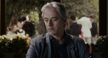 Movie still from “Certified Copy” (2010), directed by Abbas Kiarostami – A person wearing a jacket; Close Up shot, Over the shoulder angle