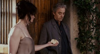 Movie still from “Certified Copy” (2010), directed by Abbas Kiarostami – A man and a woman standing next to each other holding food; Medium shot, Over the shoulder angle