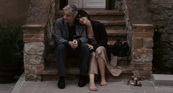 Movie still from “Certified Copy” (2010), directed by Abbas Kiarostami – A man and a woman sitting on steps; Medium shot, Overhead angle