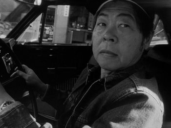 Movie still from “Chan Is Missing” (1982), directed by Wayne Wang – An older man sitting in the driver's seat of a car; Close Up shot, Low angle
