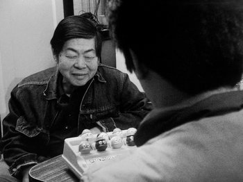 Movie still from “Chan Is Missing” (1982), directed by Wayne Wang – An older man sitting in front of an electronic device; Close Up shot, Over the shoulder angle