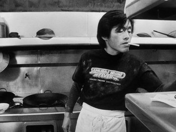 Movie still from “Chan Is Missing” (1982), directed by Wayne Wang – A man standing in a kitchen next to an oven; Medium shot, Low angle