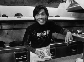 Movie still from “Chan Is Missing” (1982), directed by Wayne Wang – A black - and - white photo of a man in a kitchen; Medium shot, Low angle