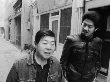 Movie still from “Chan Is Missing” (1982), directed by Wayne Wang – A man standing next to another man on the street; Medium shot, High angle