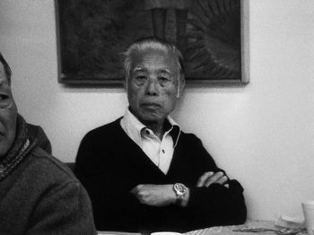 Movie still from “Chan Is Missing” (1982), directed by Wayne Wang – An older man sitting in front of a painting; Close Up shot, Low angle