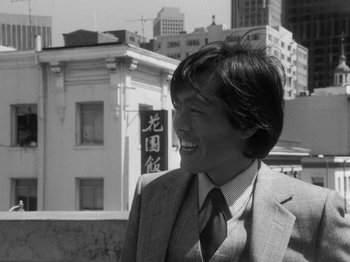 Movie still from “Chan Is Missing” (1982), directed by Wayne Wang – Black and white photograph of a man in a suit and tie; Medium shot, Low angle