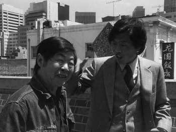 Movie still from “Chan Is Missing” (1982), directed by Wayne Wang – A man and a woman standing next to each other on the street; Medium shot, Low angle