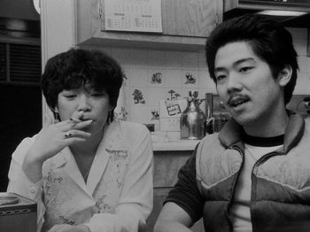 Movie still from “Chan Is Missing” (1982), directed by Wayne Wang – A man and a woman sitting next to each other in a kitchen; Close Up shot, Low angle