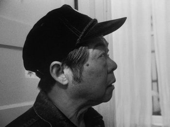 Movie still from “Chan Is Missing” (1982), directed by Wayne Wang – An older man wearing a hat looking to his left; Close Up shot, Low angle