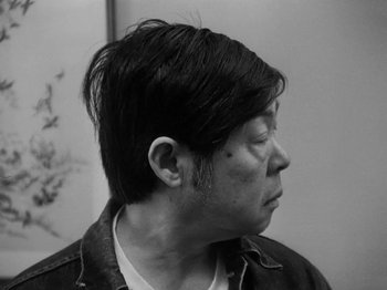 Movie still from “Chan Is Missing” (1982), directed by Wayne Wang – A black - and - white photo of a man with a shaved head; Close Up shot, Low angle