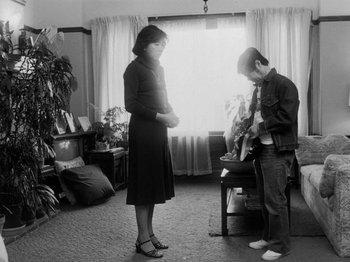 Movie still from “Chan Is Missing” (1982), directed by Wayne Wang – A woman standing next to a man in a room; Wide shot, Low angle