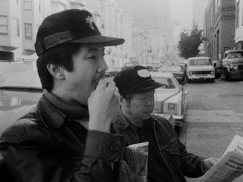 Movie still from “Chan Is Missing” (1982), directed by Wayne Wang – Two men are standing on the side of the street; Medium shot, Low angle