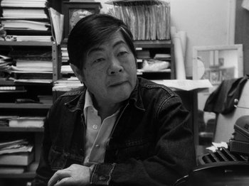 Movie still from “Chan Is Missing” (1982), directed by Wayne Wang – An older man sitting at a desk in a room; Close Up shot, High angle