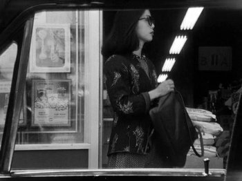 Movie still from “Chan Is Missing” (1982), directed by Wayne Wang – A black and white photo of a woman holding a bag; Medium shot, Over the shoulder angle