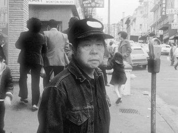 Movie still from “Chan Is Missing” (1982), directed by Wayne Wang – An older man wearing a hat standing on the sidewalk; Medium shot, Low angle