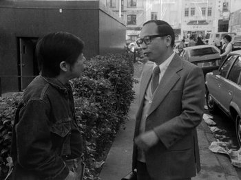 Movie still from “Chan Is Missing” (1982), directed by Wayne Wang – A man in a suit talks to a young boy; Medium shot, Over the shoulder angle
