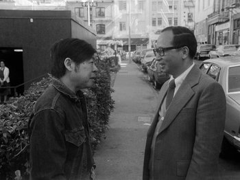 Movie still from “Chan Is Missing” (1982), directed by Wayne Wang – Two men are talking on the sidewalk of a city street; Medium shot, Over the shoulder angle
