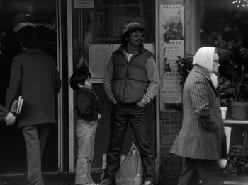 Movie still from “Chan Is Missing” (1982), directed by Wayne Wang – A man standing next to a woman on the sidewalk; Medium shot, Low angle