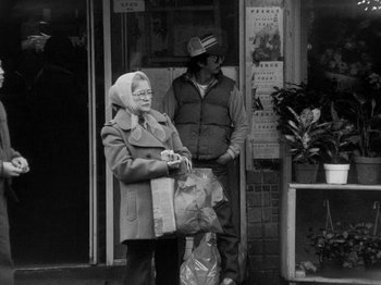 Movie still from “Chan Is Missing” (1982), directed by Wayne Wang – An older woman standing next to an older man holding bags; Medium shot, Low angle