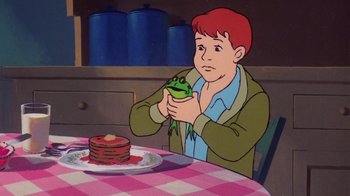 Movie still from “Charlotte's Web” (1973), directed by Iwao Takamoto – A cartoon of a boy holding a frog in front of a plate of pancakes on a table; Medium shot, High angle
