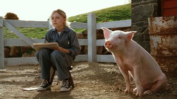 Movie still from “Charlotte's Web” (2006), directed by Gary Winick – A girl sitting on a chair next to a pig; Medium shot, Low angle