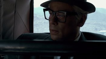 Movie still from “Che: Part Two” (2008), directed by Steven Soderbergh – A man wearing glasses and a hat sitting in a car; Close Up shot, Low angle